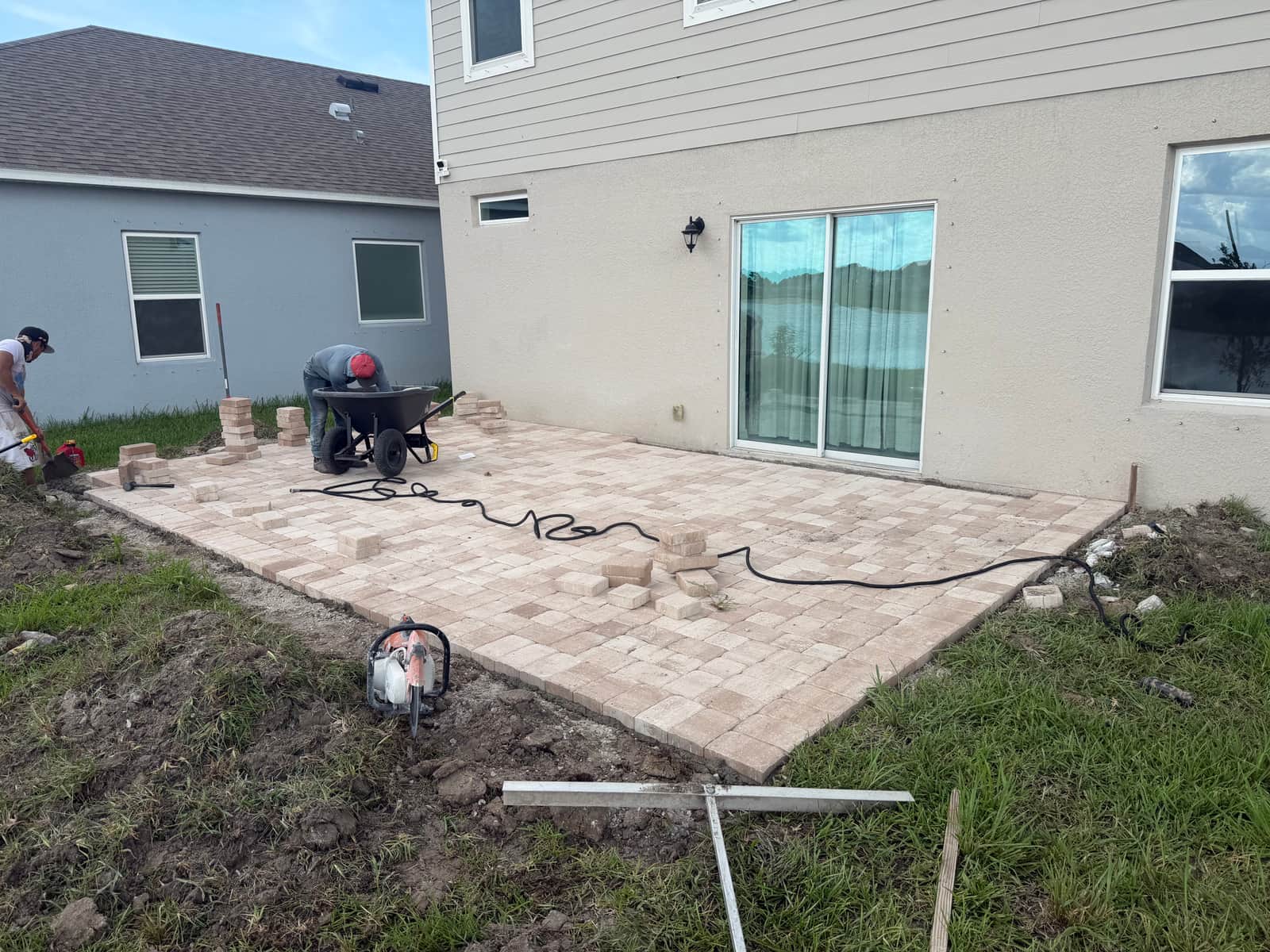 Crew compacting and edging the paver patio near the end of installation